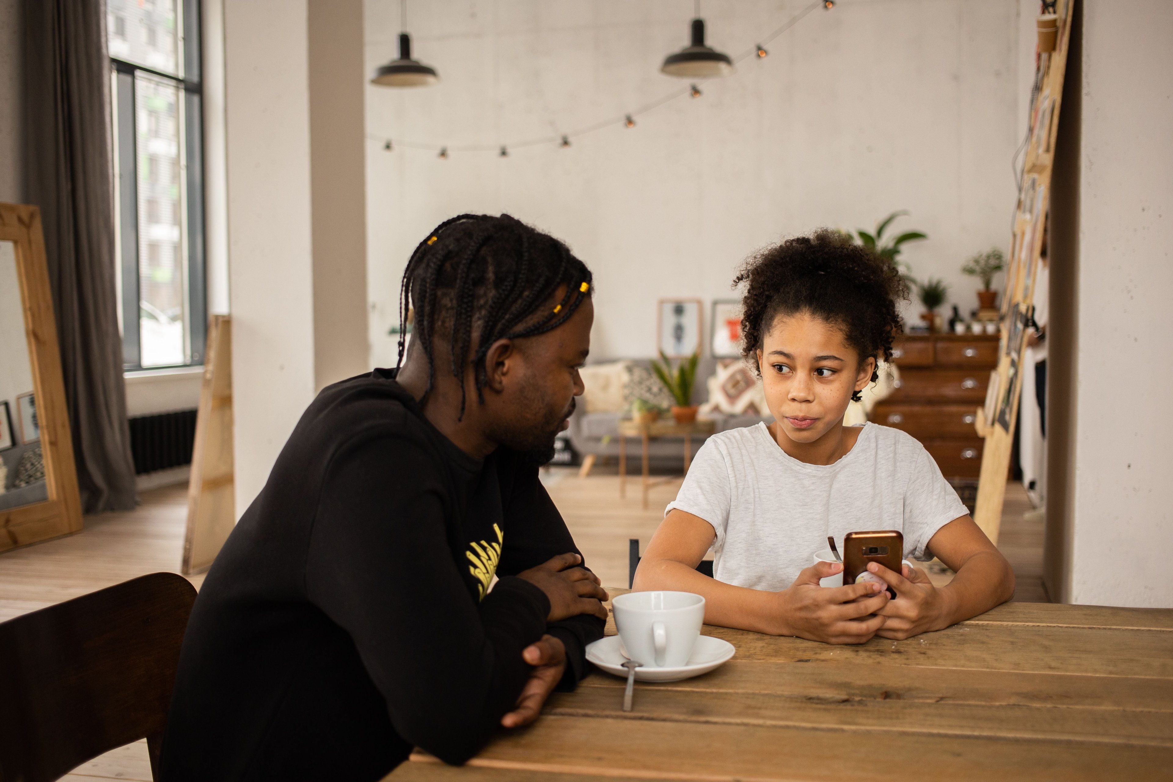 A father and daughter talking together at a table.